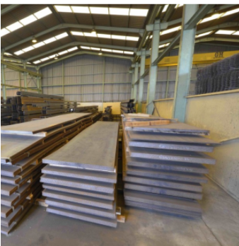 Chapas de acero apiladas sobre skids en almacén industrial