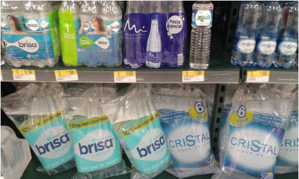Estantería de supermercado mostrando agua en botellas (arriba) y agua en bolsas plásticas (abajo)