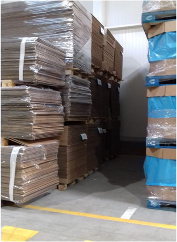 Cajas de cartón plano apiladas sobre palés en almacén